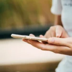 Osoba trzymająca smartfon w dłoniach i dotykająca ekranu, telefon nie reaguje.